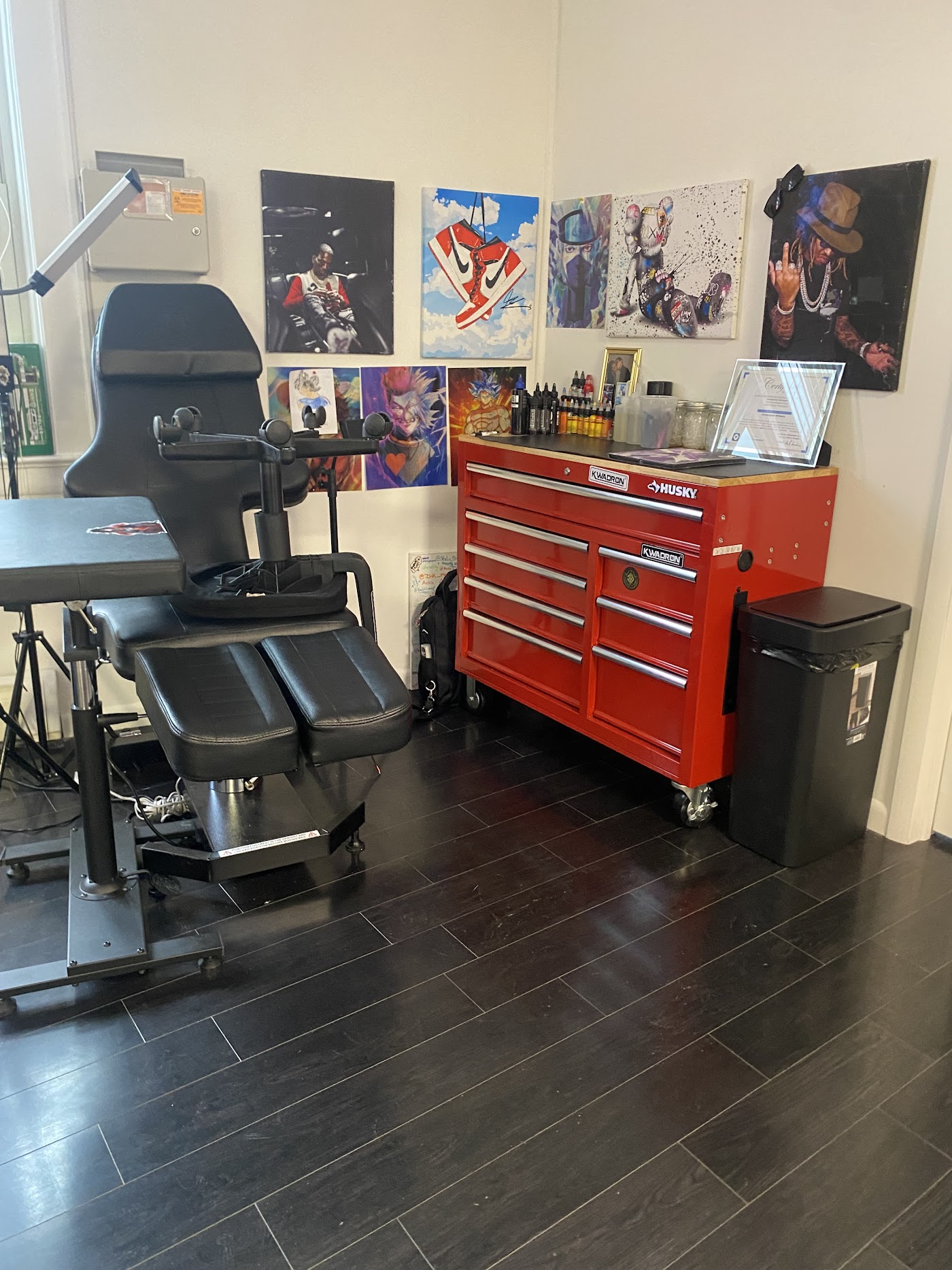 Inside S.O.C.A. Tattoo Studio: a tattoo chair beside a red tool chest stocked with inks, with original art covering the wall