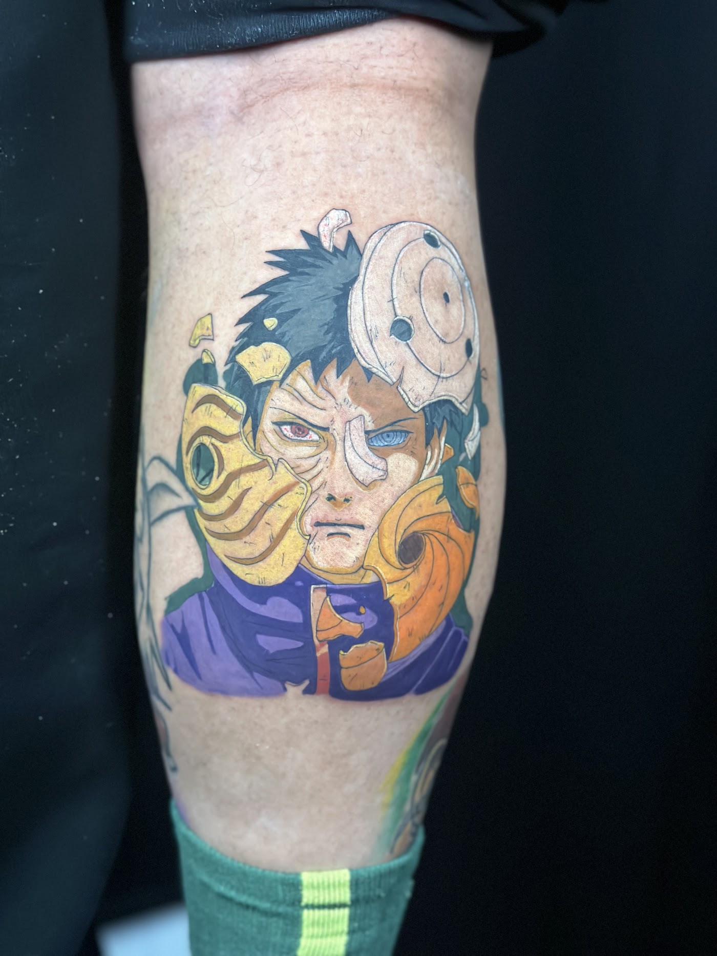 Vivid anime color tattoo of a masked character on a client's calf